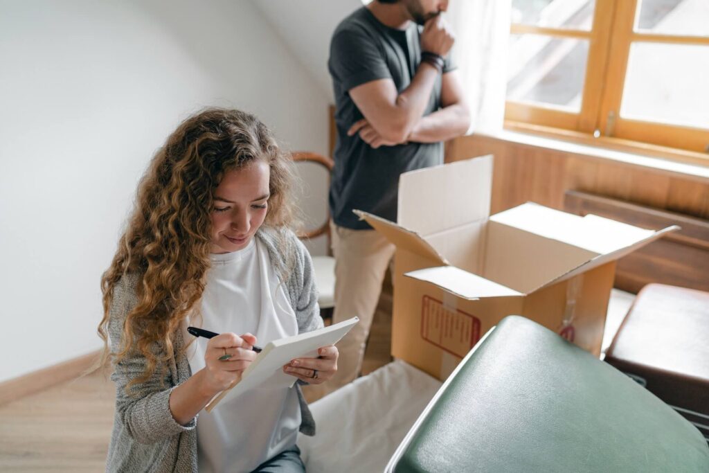 A girl making a list for moving overseas while a man behind her ponders