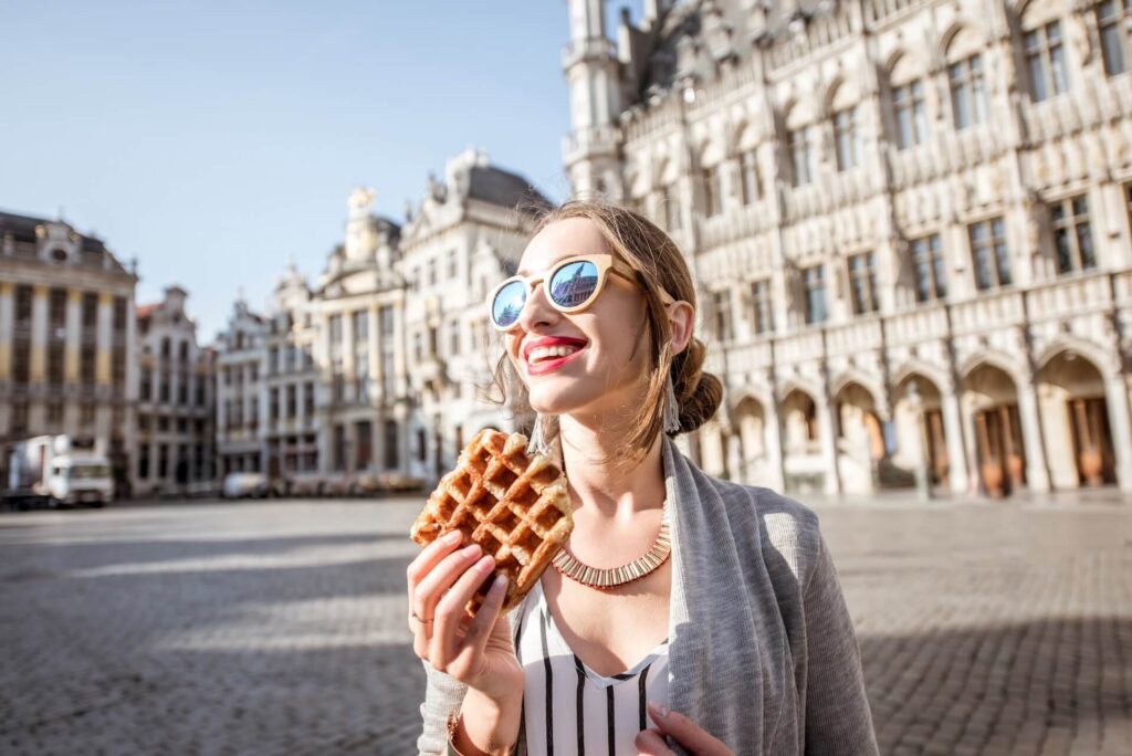 A woman smiling and eating a waffle after moving overseas
