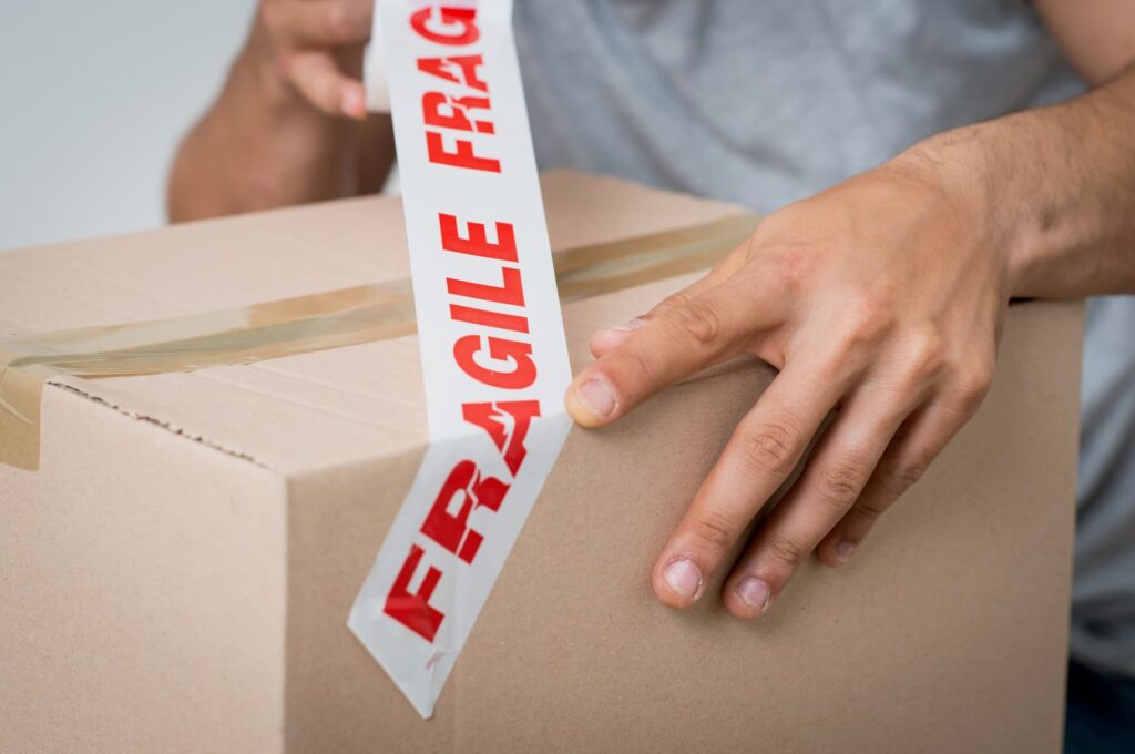 Man labeling a box with a fragile sticker