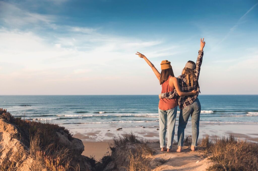 Two girls hugging, looking at the sea