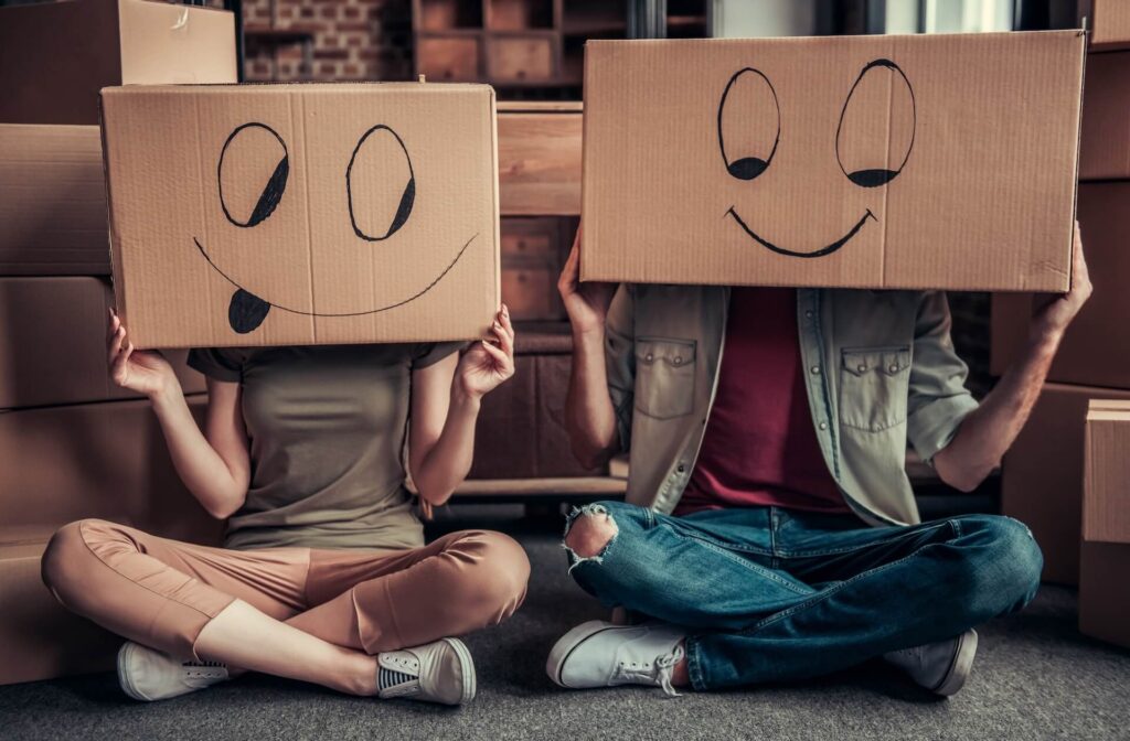 Two people holding cardboard boxes over their heads