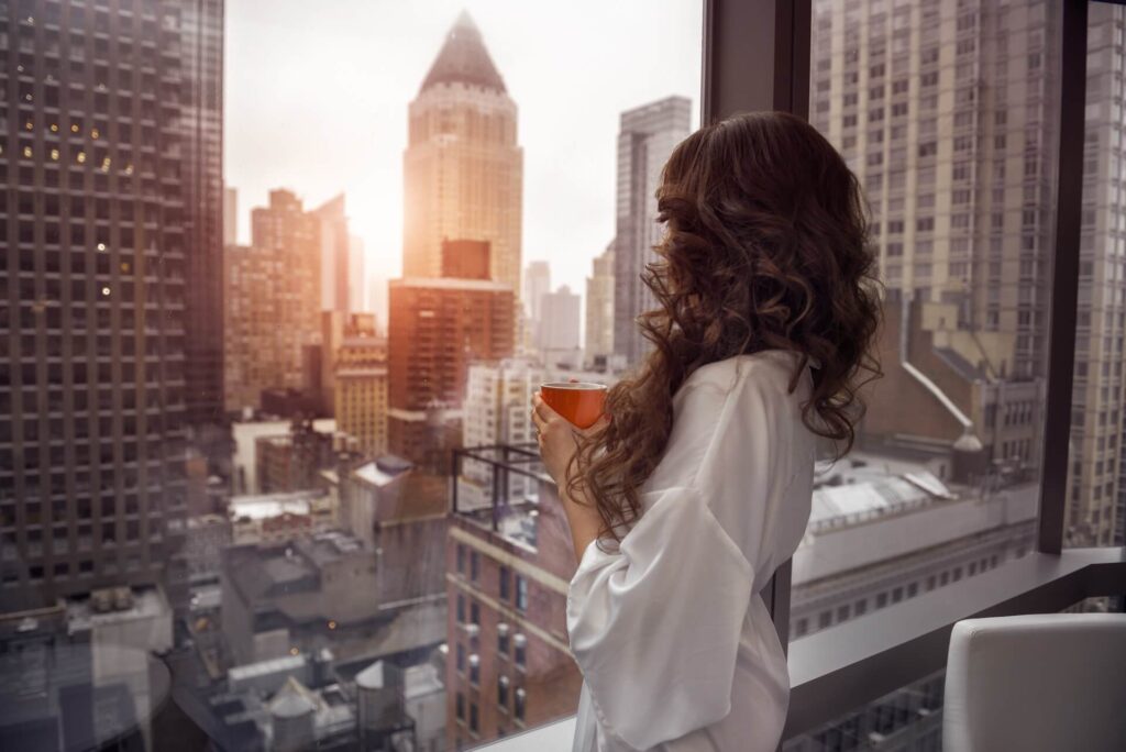 A girl drinking coffee and looking out the window after moving overseas