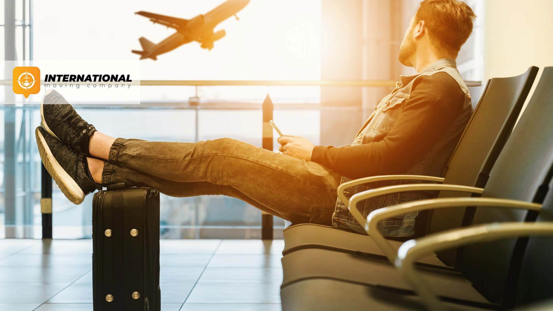 Man sitting at the airport before moving internationally International Moving Company Logo