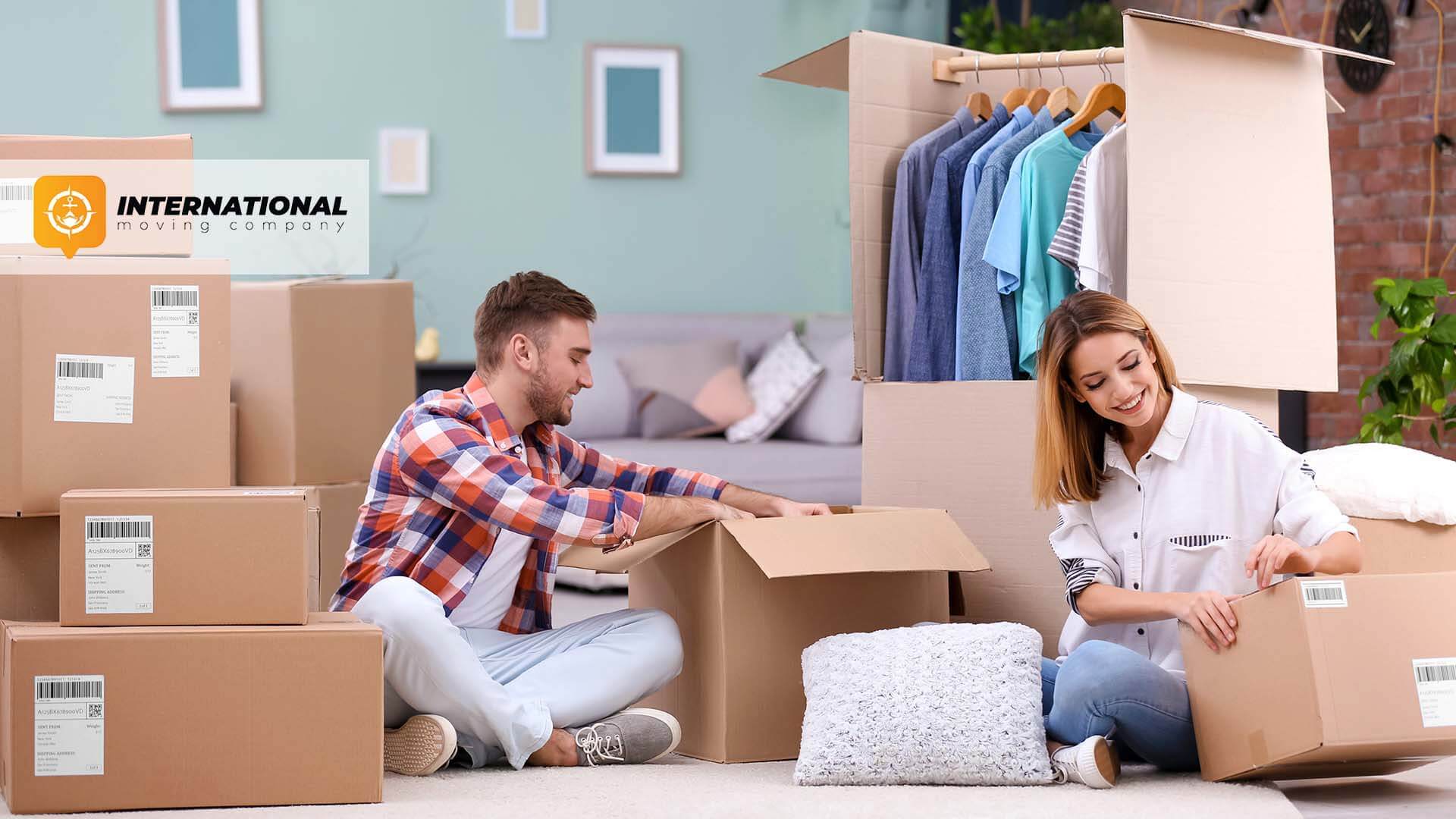 A man and a woman sitting surrounded by boxes International Moving Company logo