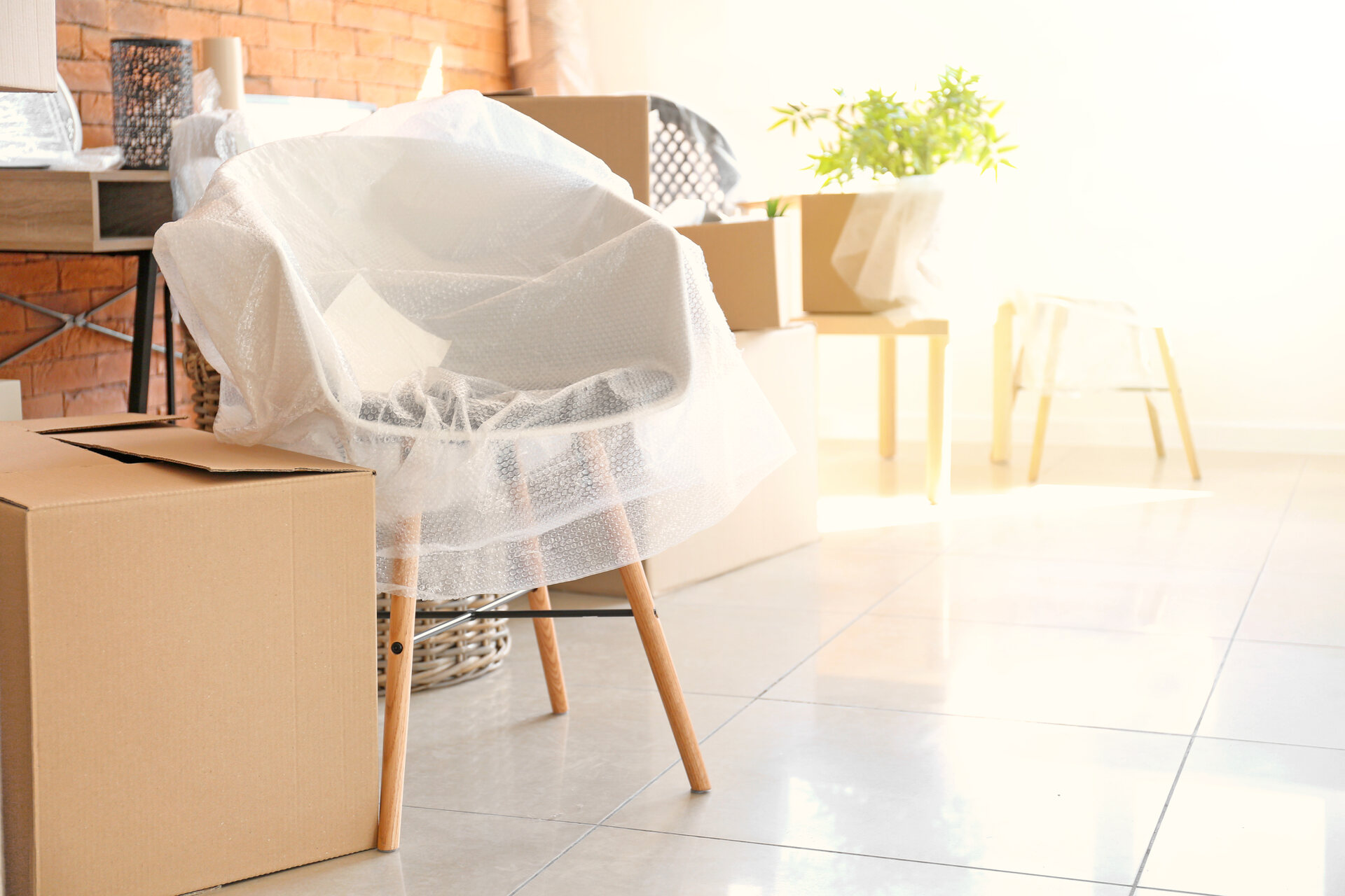 Chair wrapped in plastic wrap, surrounded by boxes for moving overseas