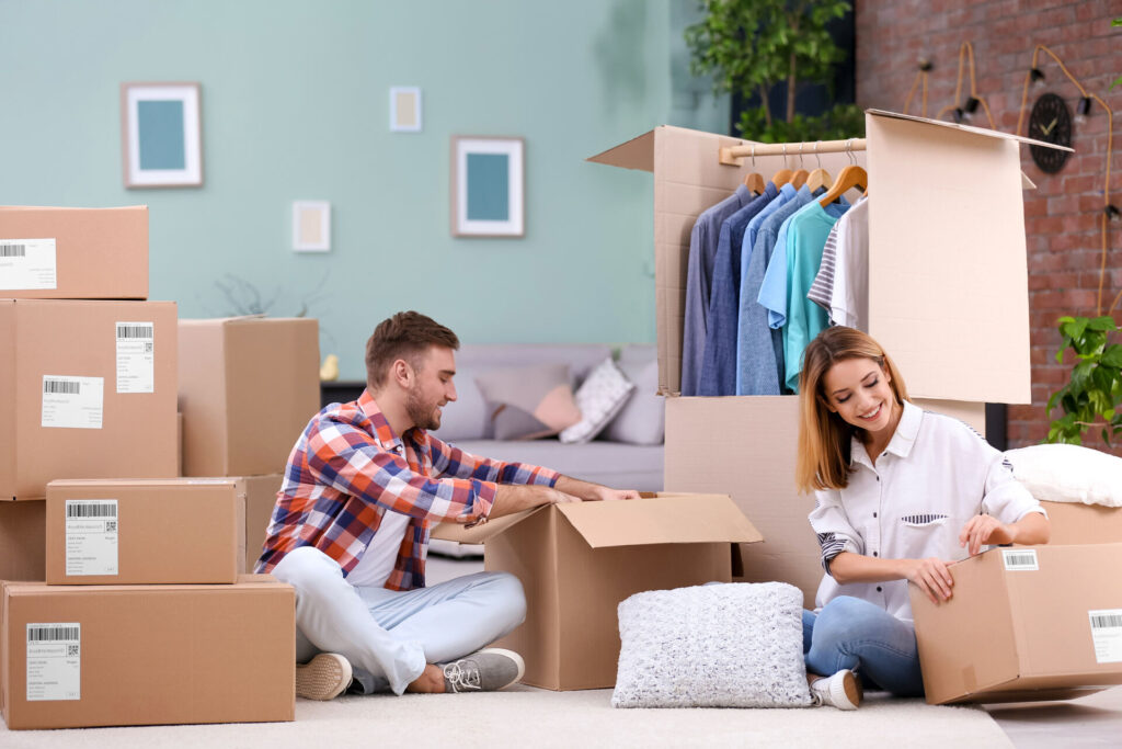 Man and woman surrounded by boxes and a wardrobe box 