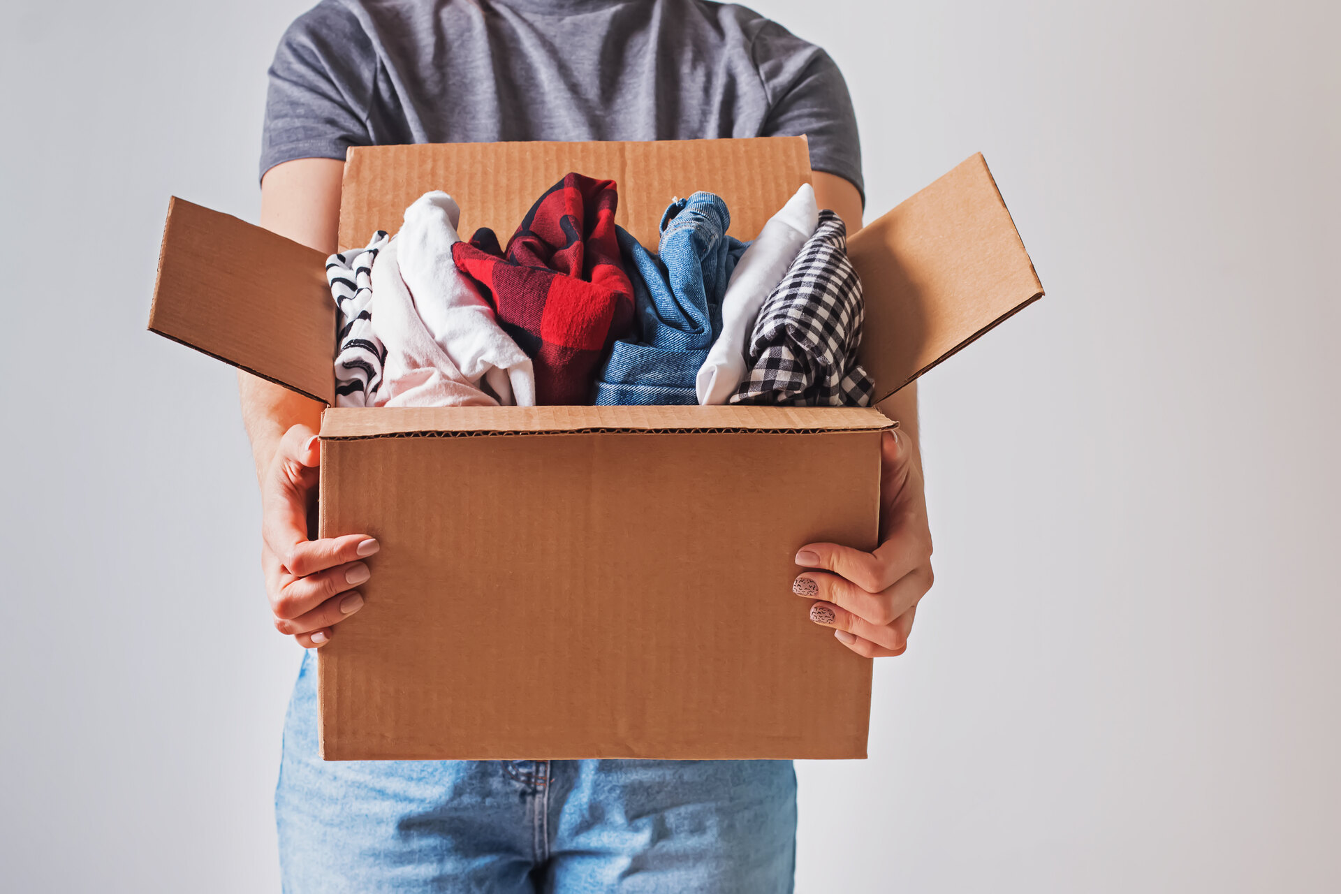 Person holding a box with clothes before moving internationally 