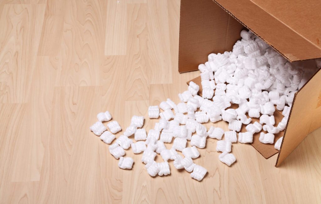Opened cardboard box with packing peanuts on the floor